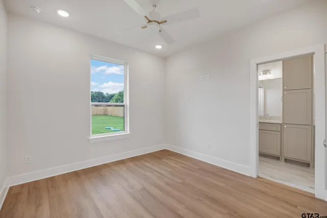 an empty room with wooden floor cabinet and windows