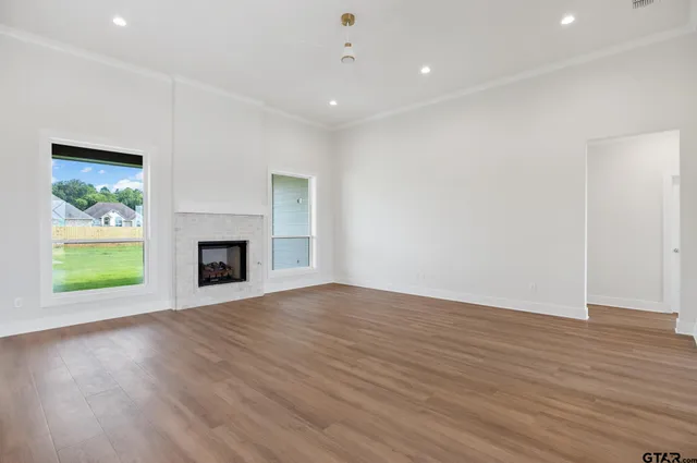 an empty room with wooden floor fireplace and windows