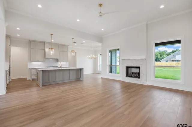 a view of an empty room with a kitchen and a fireplace