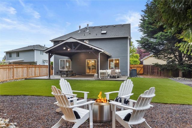 a view of a patio with table and chairs under an umbrella with large trees