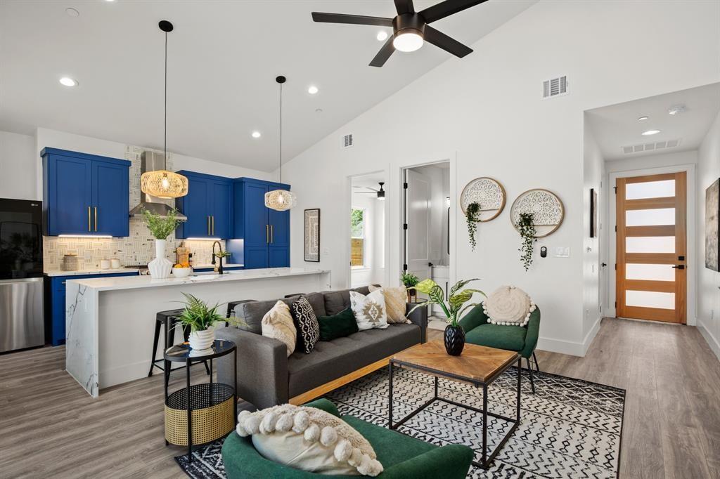 1606 Harvey Street, Unit 2 Austin, TX 78702 - Photo 1 of 22 Open-concept living area featuring vaulted ceilings, wood-finish flooring, and a modern kitchen with blue cabinetry