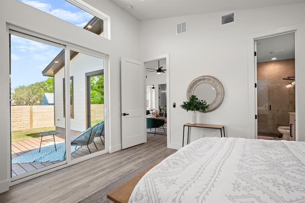 1606 Harvey Street, Unit 2 Austin, TX 78702 - Photo 11 of 22 Bedroom featuring wood-finish flooring, a full-light sliding door to an exterior deck, transom window, and a doorway to a bathroom with a glass-enclosed shower