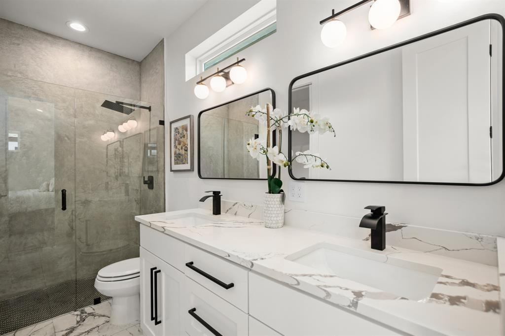 1606 Harvey Street, Unit 2 Austin, TX 78702 - Photo 13 of 22 Contemporary bathroom featuring a spacious glass-enclosed shower with a rainfall showerhead, dual vanities with integrated sinks, and matching black-framed mirrors