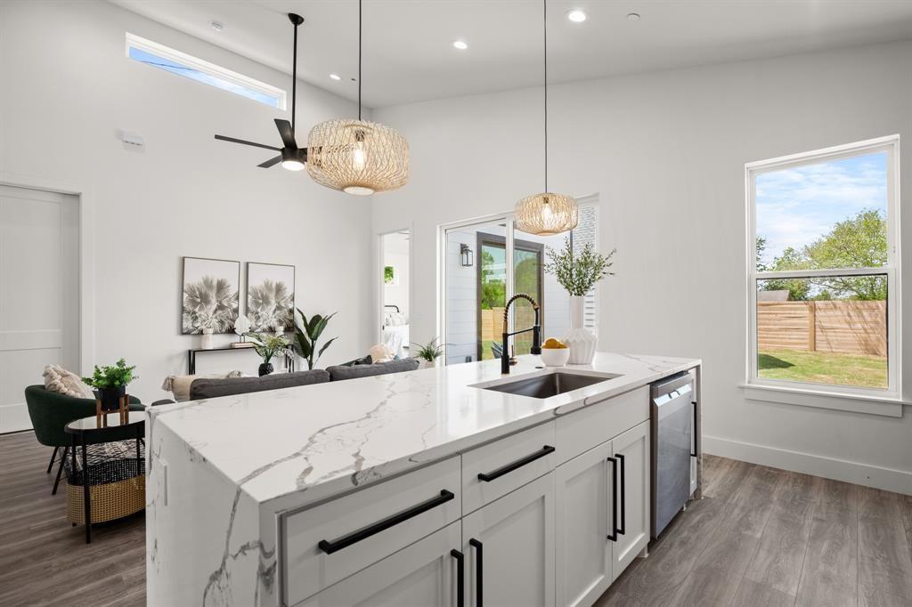 1606 Harvey Street, Unit 2 Austin, TX 78702 - Photo 8 of 22 Kitchen island featuring a waterfall countertop with a white and gray veined finish, an undermount sink with a matte black faucet, and integrated dishwasher