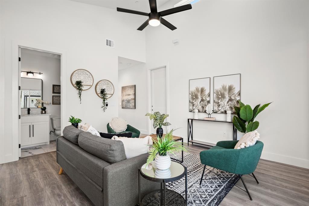 1606 Harvey Street, Unit 2 Austin, TX 78702 - Photo 10 of 22 Living area featuring vaulted ceilings, wood-finish flooring, a modern ceiling fan, and a powder room with a white vanity and dark hardware