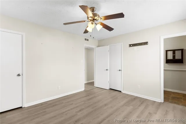 an empty room with wooden floor ceiling fan and windows