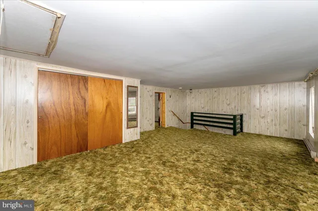 a view of a small white house with a large tree and wooden fence