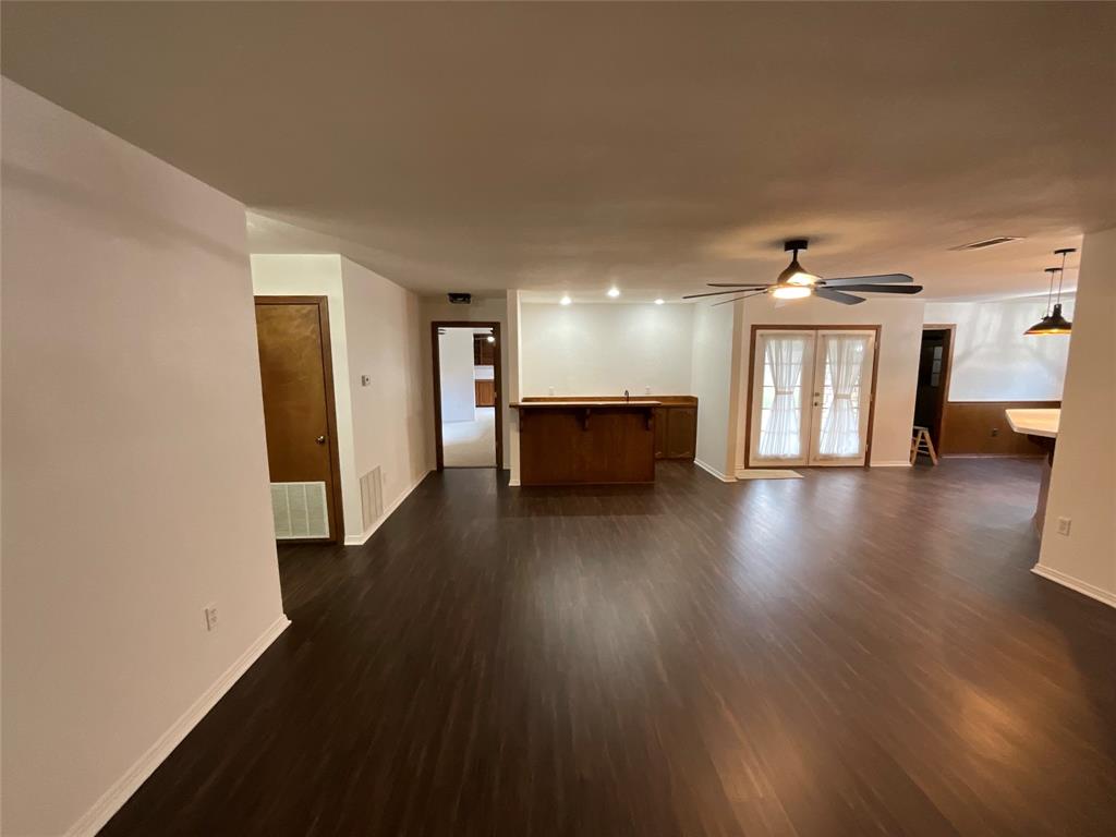 999 West Boynton Street Hamilton, TX 76531 - Photo 12 of 26 a view of a big room with wooden floor and a kitchen