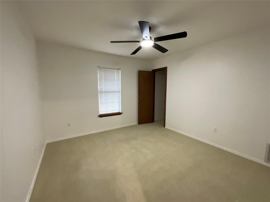 999 West Boynton Street Hamilton, TX 76531 - Photo 17 of 26 an empty room with a chandelier fan and windows