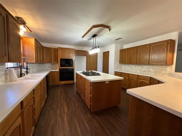 a large kitchen with stainless steel appliances kitchen island granite countertop a stove a sink dishwasher and a refrigerator with wooden floor