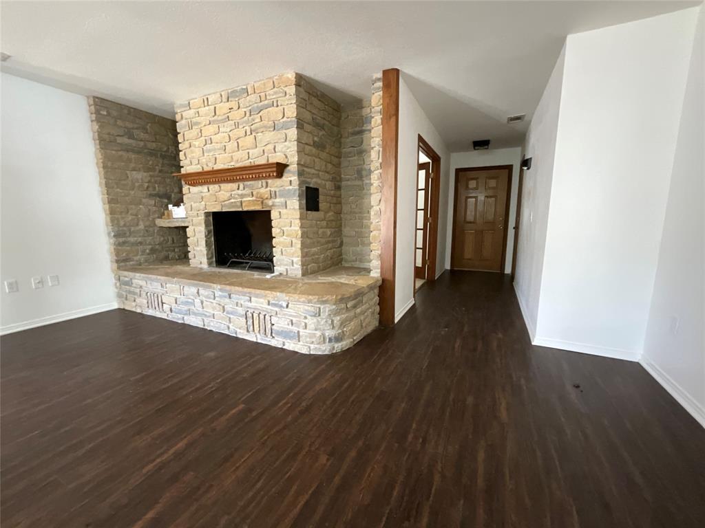 999 West Boynton Street Hamilton, TX 76531 - Photo 22 of 26 a view of empty room with wooden floor and fireplace