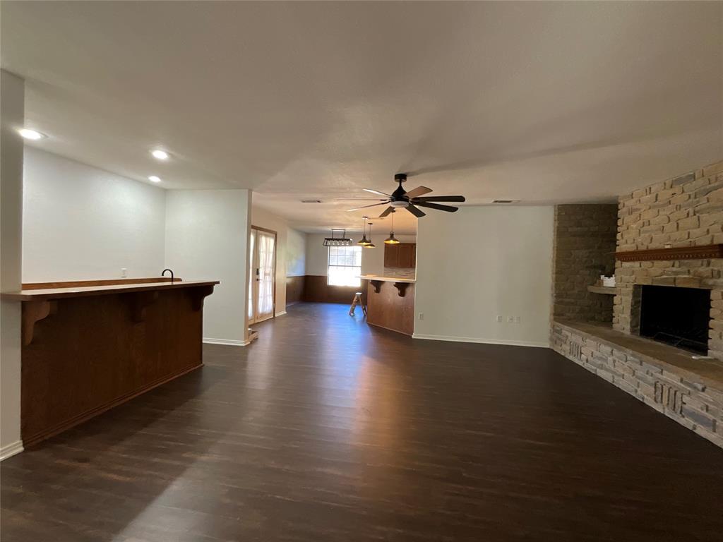999 West Boynton Street Hamilton, TX 76531 - Photo 23 of 26 a view of a big room with wooden floor a fireplace and a window