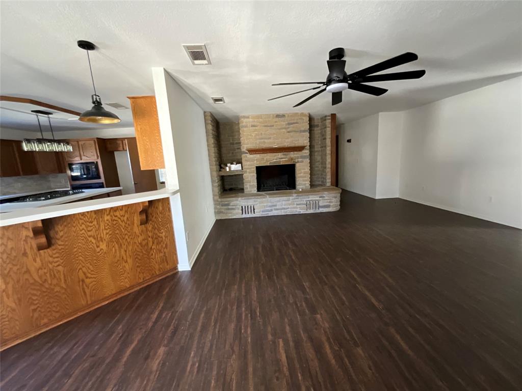 999 West Boynton Street Hamilton, TX 76531 - Photo 25 of 26 a view of a livingroom with wooden floor a ceiling fan and staircase