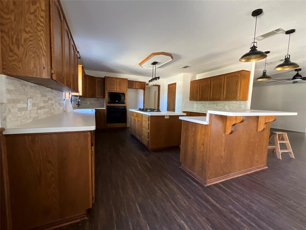 999 West Boynton Street Hamilton, TX 76531 - Photo 26 of 26 a kitchen with stainless steel appliances granite countertop a refrigerator a stove top oven a sink dishwasher and wooden floor