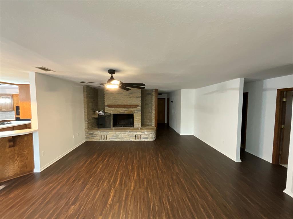 999 West Boynton Street Hamilton, TX 76531 - Photo 9 of 26 a view of empty room with wooden floor and fireplace