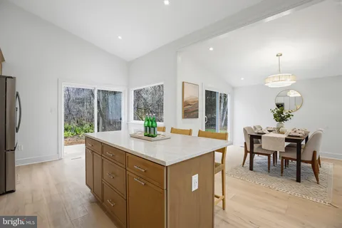 a room with kitchen island granite countertop wooden floor cabinetry and chandelier