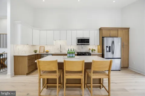 a kitchen with stainless steel appliances a dining table chairs microwave and sink