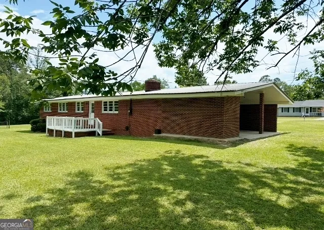 a backyard of a house with table and chairs a barbeque and a large tree