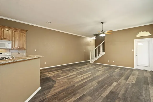 a view of an empty room with window and wooden floor