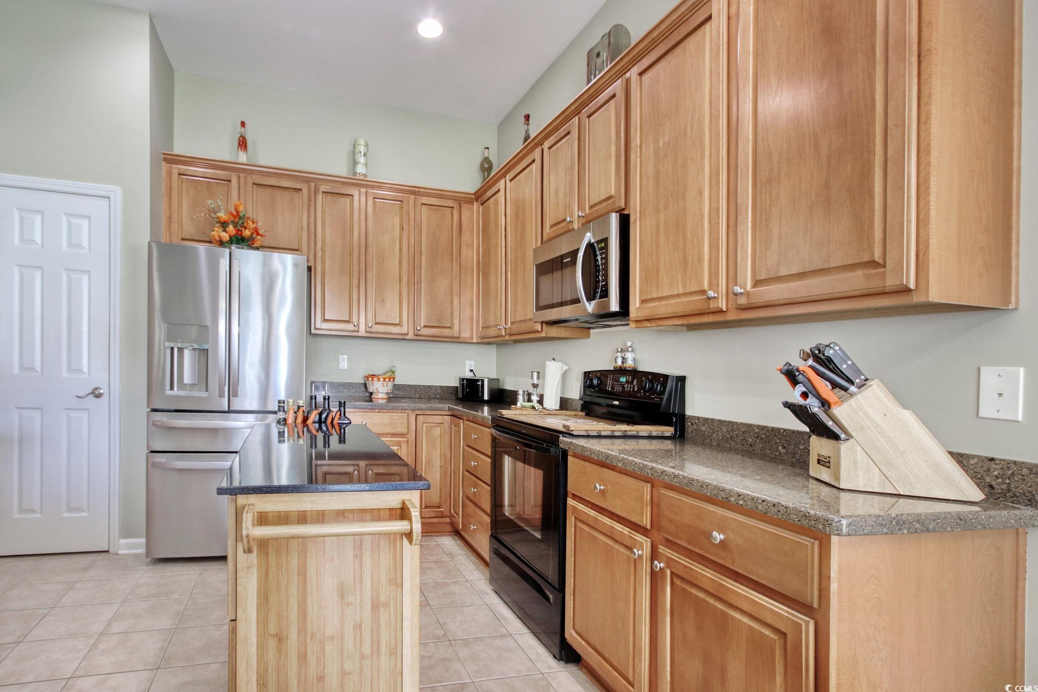 47 Pinfeather Drive Murrells Inlet, SC 29576 - Photo 11 of 35 Kitchen with stainless steel appliances, a center island, light tile patterned flooring, and dark stone countertops