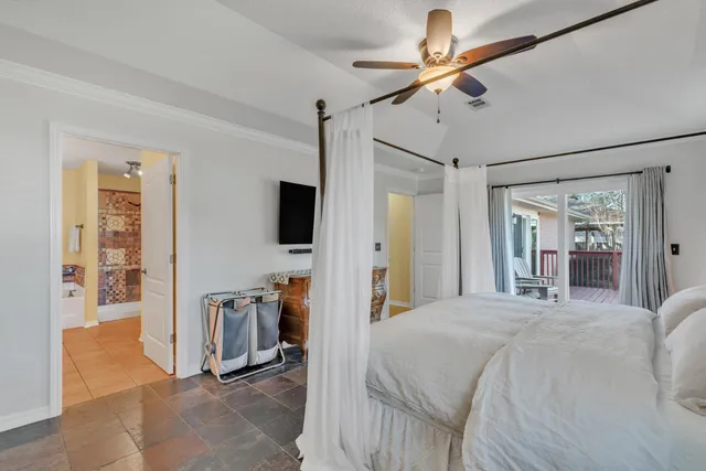 a bedroom with a bed a flat screen tv and a chandelier