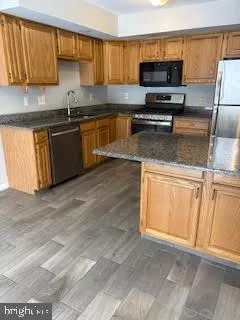 a kitchen with stainless steel appliances granite countertop a sink a stove and a microwave