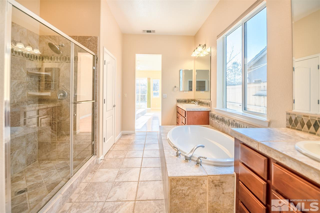 10645 Summer Glen Drive Reno, NV 89521 - Photo 22 of 25 a bathroom with a granite countertop sink a mirror and a shower