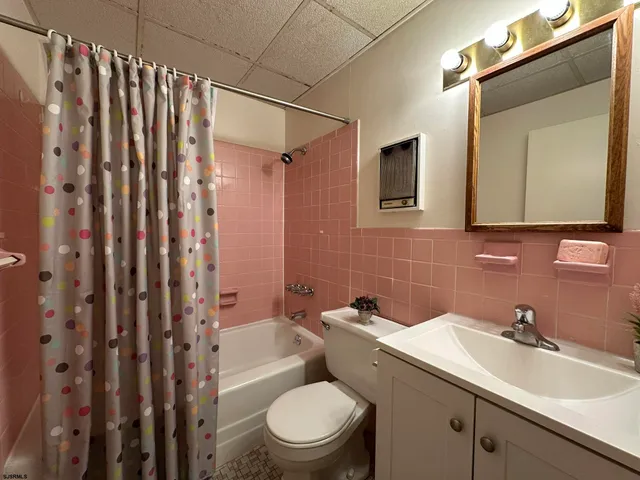 a bathroom with a sink a toilet a mirror and shower curtain