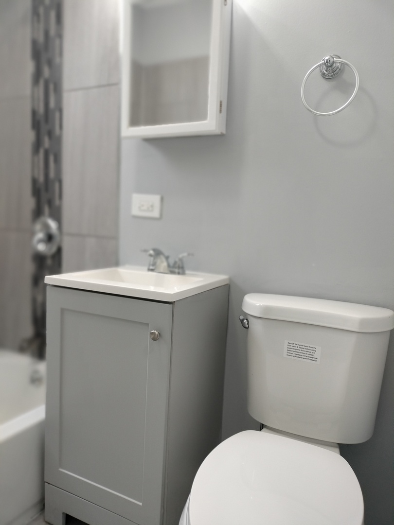 6601 South Green Street, Unit 8171 Chicago, IL 60621 - Photo 17 of 28 a white toilet sitting next to a bathroom sink