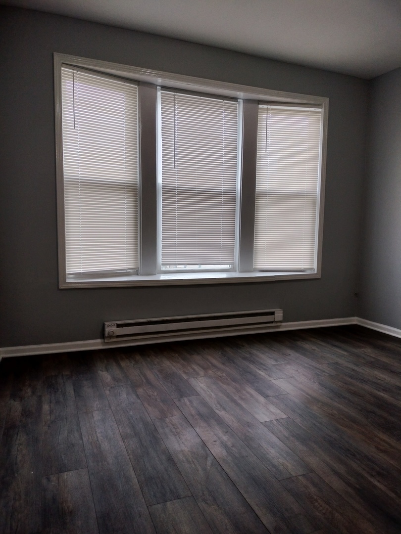 6601 South Green Street, Unit 8171 Chicago, IL 60621 - Photo 2 of 28 an empty room with wooden floor and a window