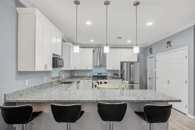 a kitchen with stainless steel appliances granite countertop a sink a stove a refrigerator and island with wooden floor