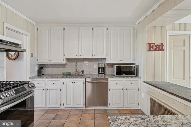 a kitchen with white cabinets and appliances