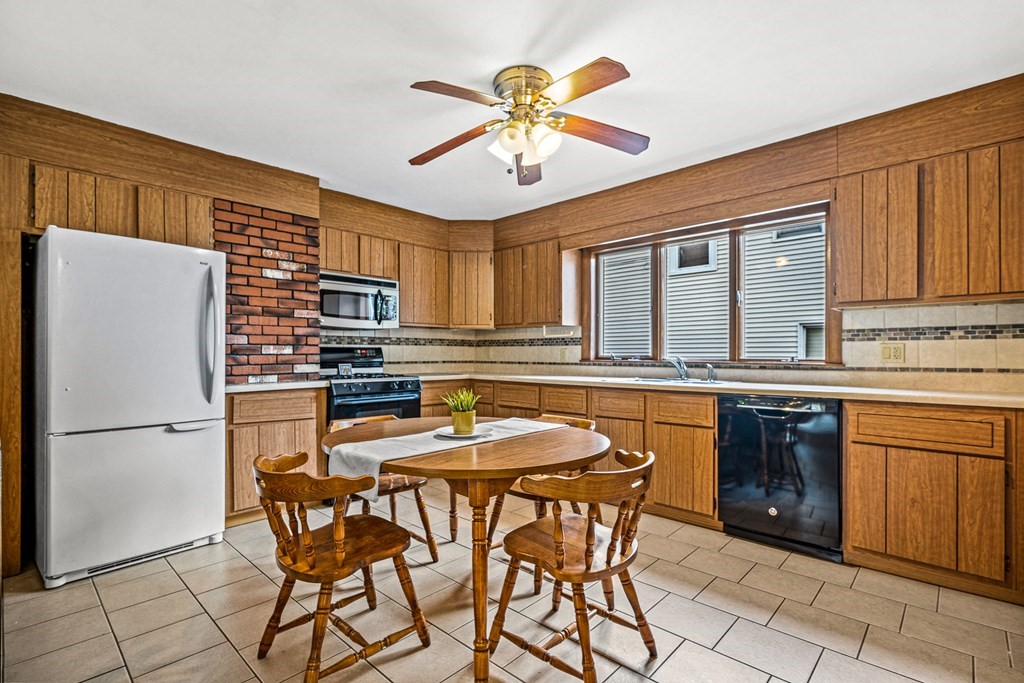 14 Hancock Street Stoneham, MA 02180 - Photo 7 of 38 a kitchen with stainless steel appliances granite countertop a refrigerator a sink a stove a dining table and chairs