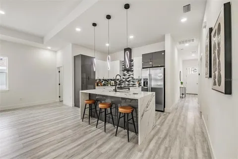 a kitchen with stainless steel appliances kitchen island granite countertop a refrigerator a stove a sink dishwasher and a dining table with wooden floor