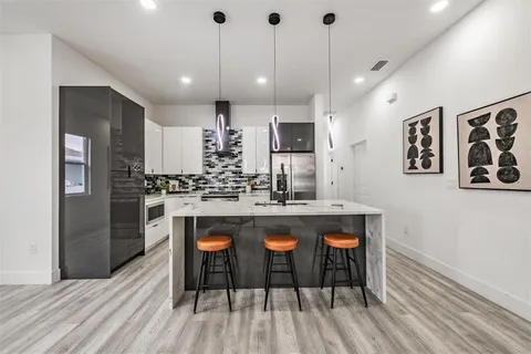 a kitchen with stainless steel appliances kitchen island granite countertop a wooden floor and white cabinets