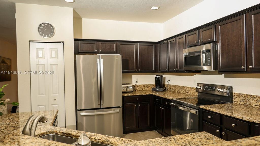 11601 Southwest 232nd Lane Homestead, FL 33032 - Photo 7 of 32 a kitchen with granite countertop a refrigerator stove and microwave