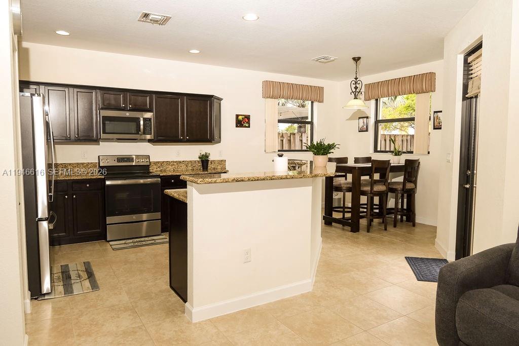 11601 Southwest 232nd Lane Homestead, FL 33032 - Photo 8 of 32 a kitchen with stainless steel appliances kitchen island granite countertop a sink a stove and a refrigerator