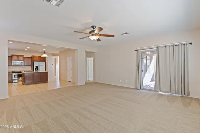 a view of a livingroom with a chandelier fan and wooden floor