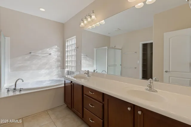 a spacious bathroom with a double vanity sink a large mirror and a bathtub