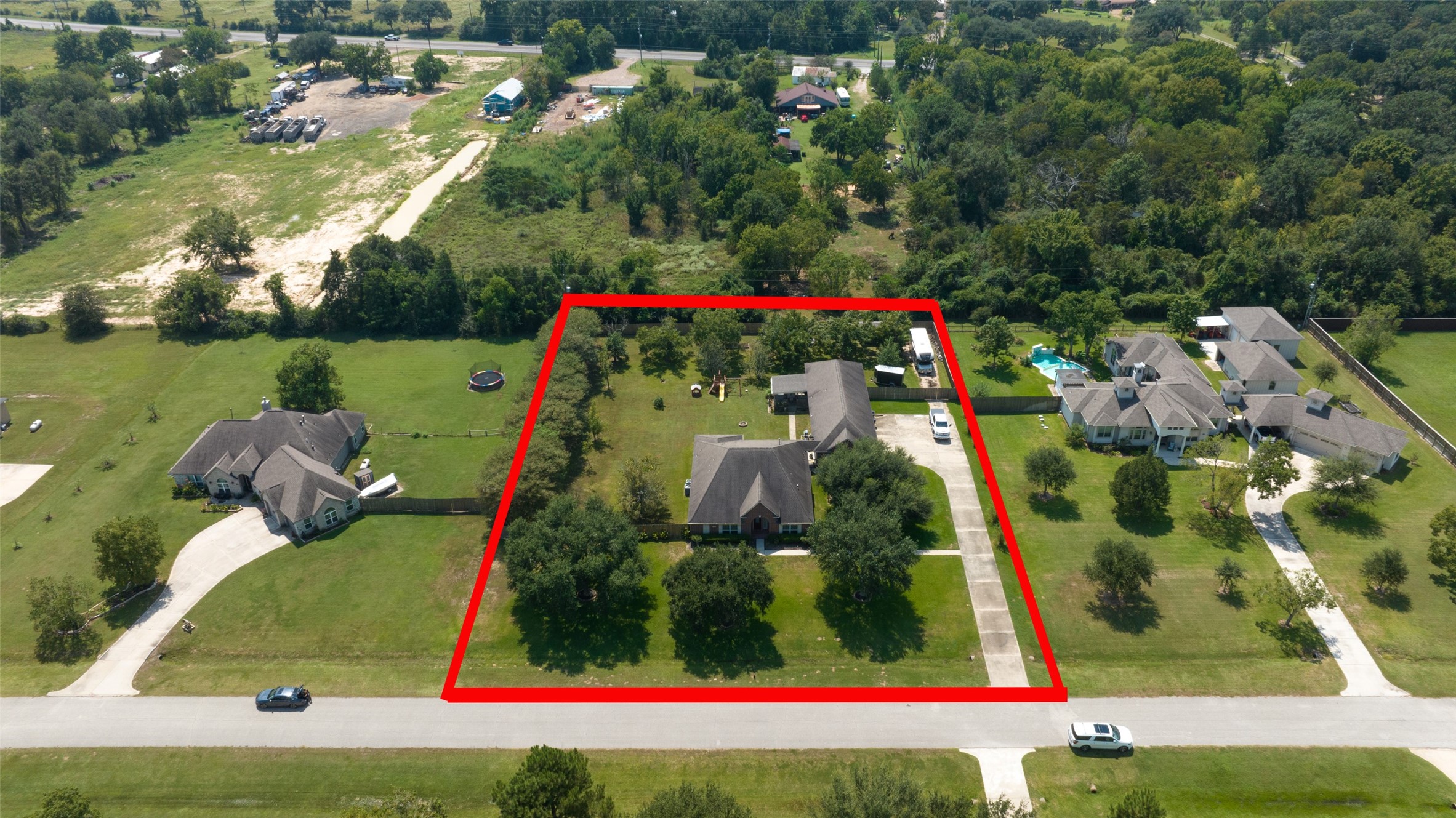 2203 Red Bird Lane Pattison, TX 77423 - Photo 3 of 46 This aerial photo shows a spacious property outlined in red, featuring a large home with a long driveway and ample green space. It's situated in a suburban area with neighboring houses, surrounded by trees for added privacy.