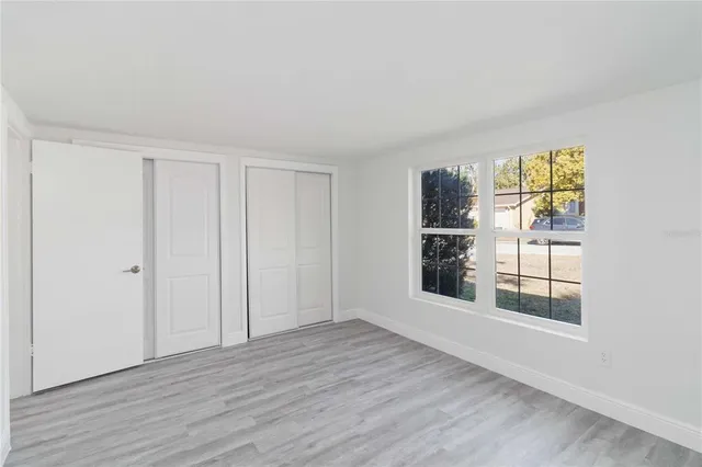 a view of an empty room with a window and wooden floor