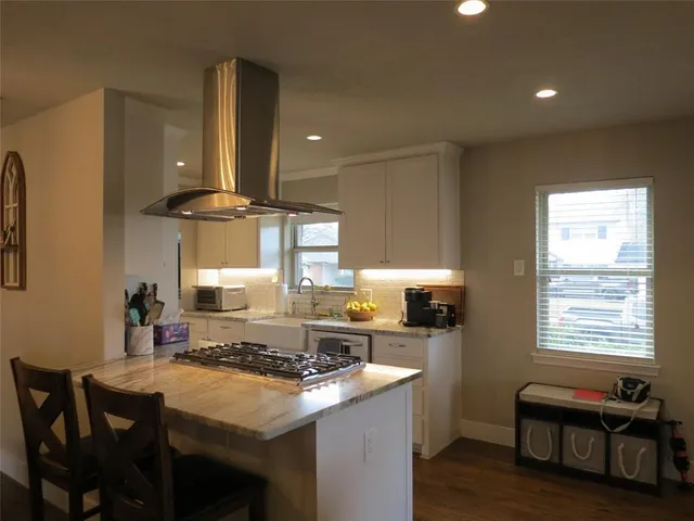 a kitchen with kitchen island a stove a sink a dining table and chairs