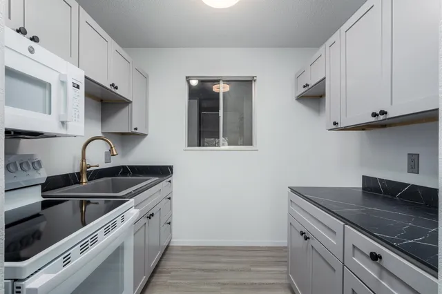 a kitchen with granite countertop a sink stove and cabinets