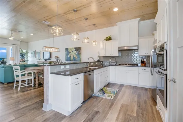 a kitchen with a sink stove cabinets and wooden floor