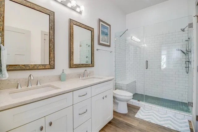 a bathroom with a double vanity sink toilet mirror and shower
