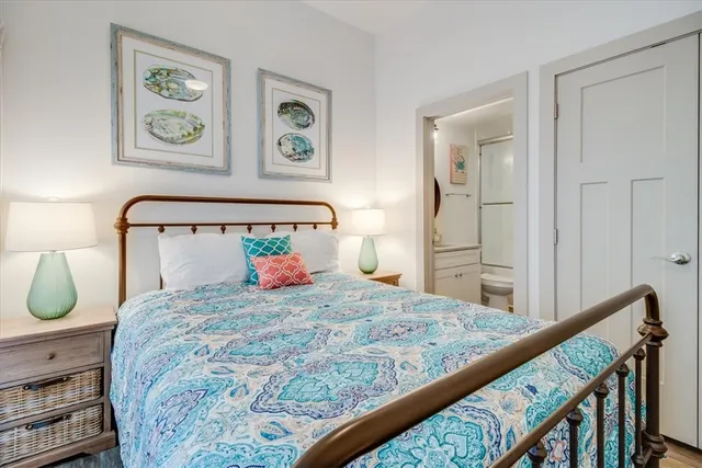 a bedroom with a bed a painting on the wall and a window