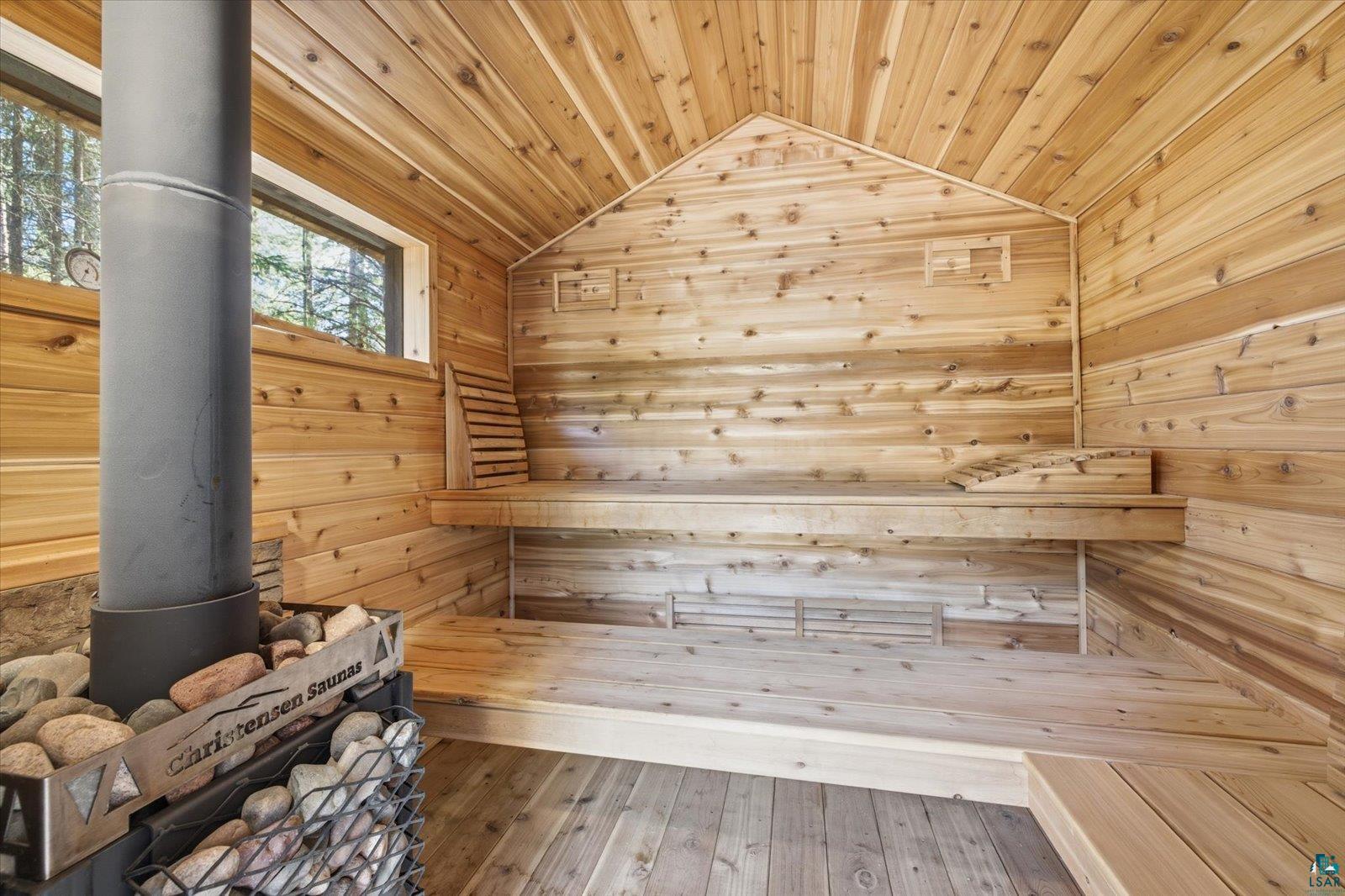 7185 Giants Ridge Road Embarrass, MN 55732 - Photo 36 of 47 Cedar-lined sauna featuring a metal wood-burning stove with a rock basket, built-in benches, two windows, and vaulted wood-paneled ceilings