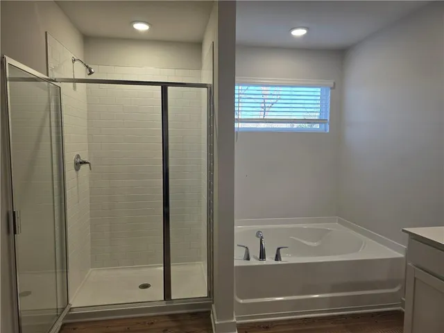 a bathroom with a bathtub a shower and a window