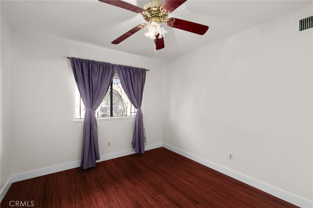 9637 Apricot Avenue Rancho Cucamonga, CA 91737 - Photo 24 of 44 an empty room with wooden floor chandelier fan and windows