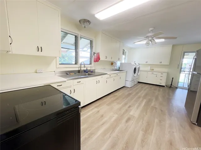 a kitchen with a sink dishwasher a stove and white cabinets with wooden floor